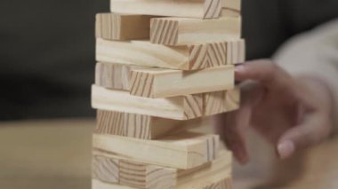 İnsanlar bir masa başı oyunu sırasında ahşap blok kulesini yeniden birleştiriyorlar, denge, işbirliği ve evdeki rahat sosyal oyun üzerine odaklanıyorlar..