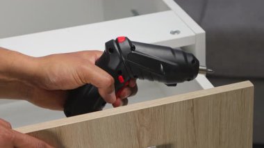 Bir marangozun mutfak çekmecesini tornavidayla bağlayıp profesyonel ahşap işçiliği ve mobilya montaj becerilerini vurguladığı ayrıntılı bir fotoğraf..