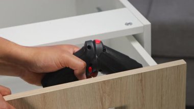 Profesyonel marangoz ahşap çekmeceyi ayarlamak için elektrikli matkap kullanıyor, el işçiliği, el işi, tamirat ve mobilya montajını temsil ediyor..