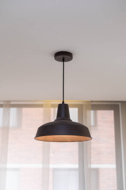 Close-up of a hanging ceiling lamp with warm illumination, used as a decorative lighting element in a contemporary interior environment.