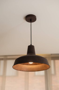 Minimalist tavan kolyesi lambası açıldı, modern bir iç mekanda sıcak ışık sağlıyor, ev ışıklandırmasını, iç tasarımı ve rahat atmosferi temsil ediyor..