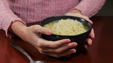 Kaşıkla yemek yerken bir kase ramen eriştesi tutarken, rahat yemek, sıradan yemek ve basit ev yemeği gösterirken ellerinizi kapayın..