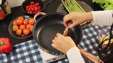 Bir kadın sıcak tavada taze tavuk filetosu pişiriyor, ev yapımı sağlıklı bir yemek yaratıyor ve elleriyle yemek pişirme aktivitelerini gösteriyor..