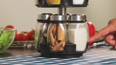 Baharat rafından tarçın seçen, malzeme seçimini, yemek hazırlığını ve düzenli mutfak düzenini gösteren bir eli kapatın..