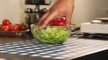 Bir elin marulu sudan çıkarması ve suyunu boşaltması, sebze yıkama sürecini, tazeliği ve sağlıklı mutfak hazırlama rutinini gösteriyor..