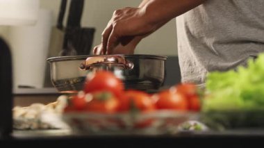 Aşçı ellerinin tencerede ahşap bir kaşıkla güveç karıştırıp pişirme işlemini, ev yapımı yemek hazırlığını ve sıcak mutfak rutinini göstermesi..