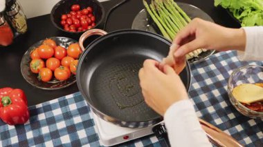 Kadın ellerinin sıcak tavaya çiğ tavuk göğsü koyması yemek pişirme, yemek hazırlama ve mutfak düzeninde ev yapımı yemekleri temsil ediyor..