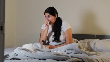 Kadın yatakta uzanıp duygusal bir film seyrediyor ve burnunu kağıt mendille silerken ağlıyor. Üzüntüyü, empatiyi ve kişisel duygusal anı temsil ediyor..