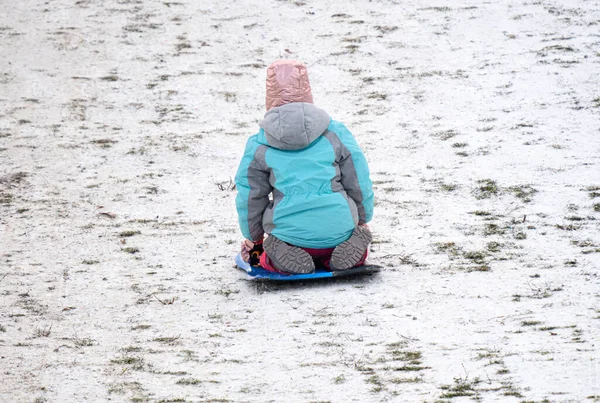 雪の丘をそりに乗っている無名の少女は — ストック写真