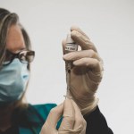 Enfermeiro puxa a sua vacinação vívida para uma seringa