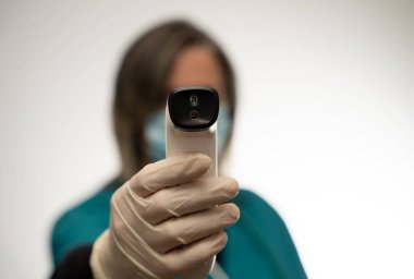 Doktor ateşini ölçmek için bir el termometresi tutuyor.