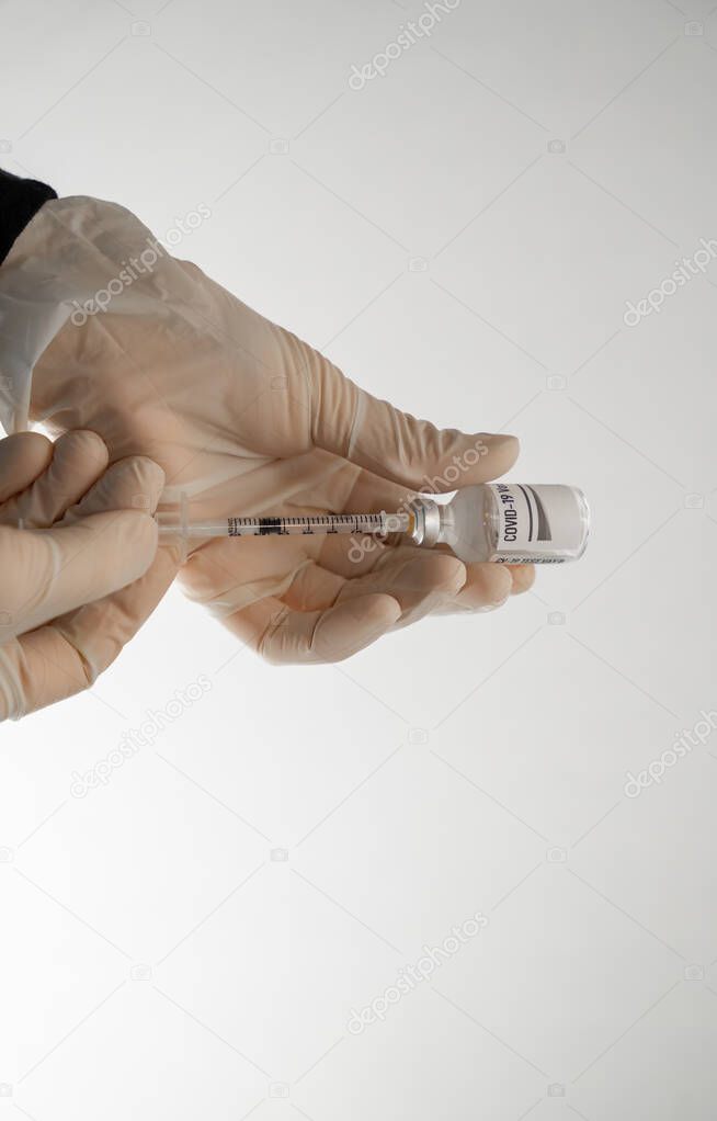 gloved hands are drawing a covid 19 vaccination into an awaiting syringe