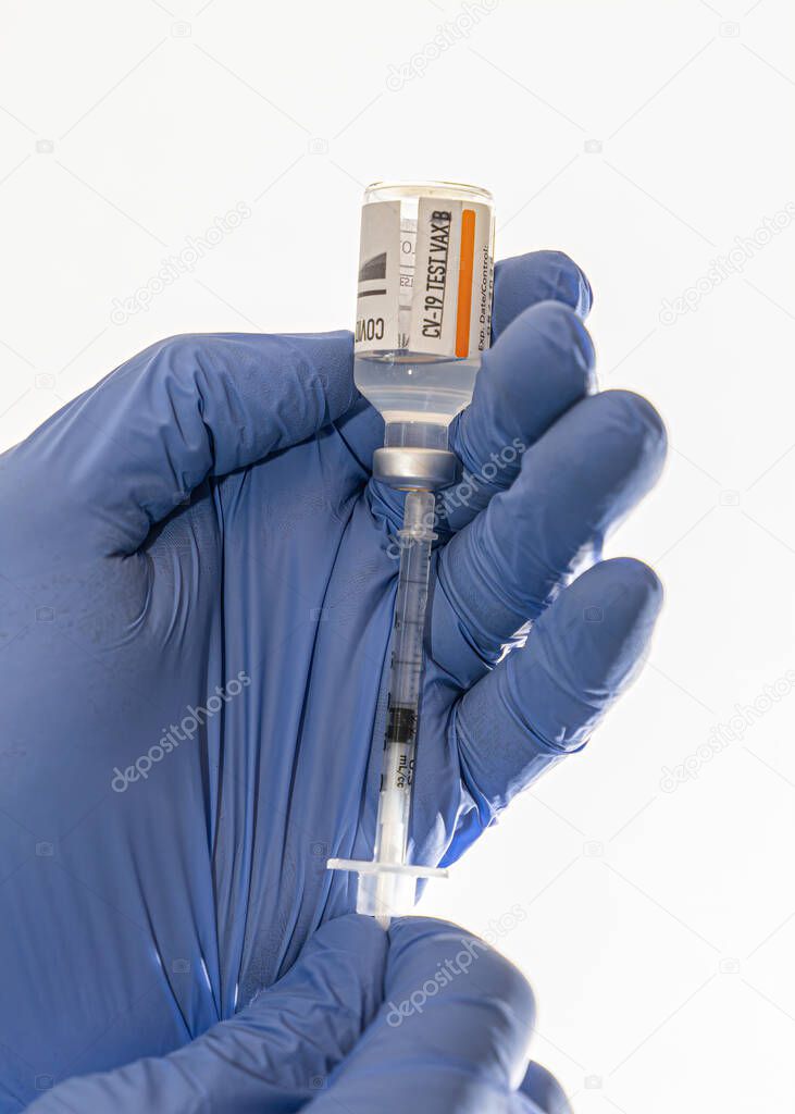 gloved hands are drawing a covid 19 vaccination into an awaiting syringe