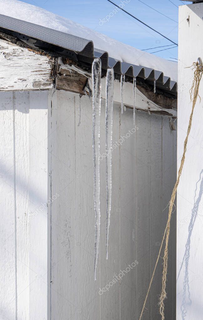 frozen icicles are hanging from the roof after a winter storm