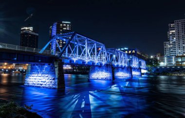 Grand Rapids, Michigan  USA - October 9 -2020: Blue Bridge of downtown Grand Rapids glows vibrant after dark clipart
