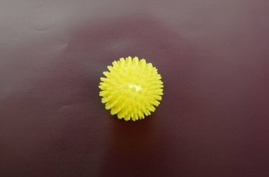 Beyaz arka planda iğneler olan sarı masaj topu.