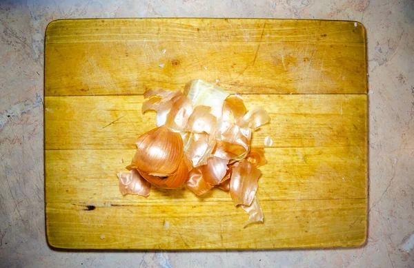 木製のまな板の上に玉ねぎの殻 — ストック写真
