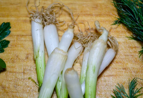 Green onion bulbs on a wooden cutting board in close-up — Stock Photo, Image