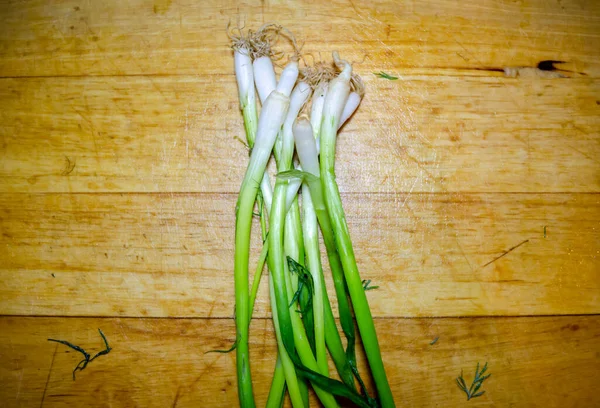 Bundle of green onion on a wooden cutting board in close-up — Stock Photo, Image