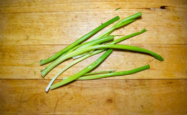 Green onion stems on wooden cutting board in close-up — Stock Photo, Image