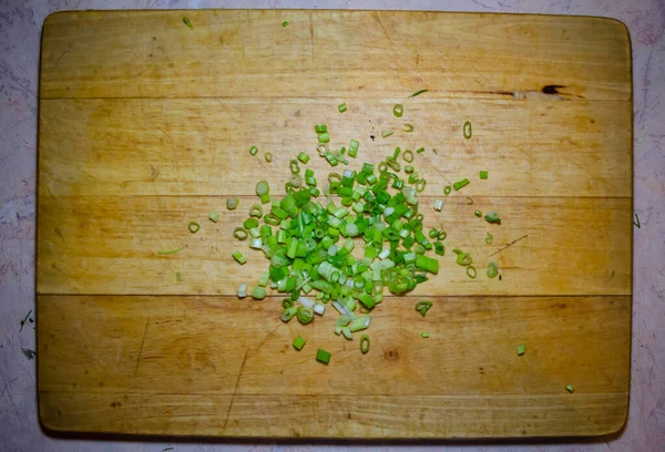 Cipolle verdi finemente tagliate su una tavola di legno per il taglio — Foto Stock