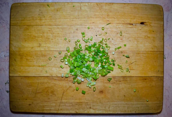 Fijn gesneden groene uien op een houten plank voor het snijden — Stockfoto