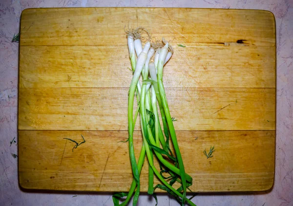 Paquete de cebolla verde en una tabla de cortar de madera en primer plano —  Fotos de Stock
