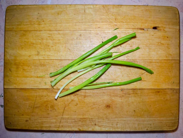 Tallos de cebolla verde en tabla de cortar de madera en primer plano —  Fotos de Stock