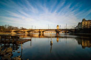 Berrak su yansıması ile Vltava nehir köprüsü ve tekne inanılmaz gündoğumu görünümü. Tipik Prag güneşli sabah. Eski şehir sabah manzarası. Prag Çek Cumhuriyeti.