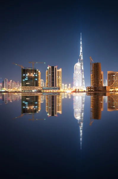 Fascinating reflection of tallest skyscrapers in Business Bay district during calm night. Downtown summer night. Construction built at night time. Dubai, United Arab Emirates.