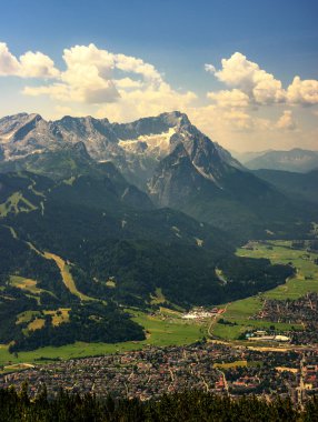 En yüksek dağ tepe Zugspitze ve Alpspix ile Garmisch Partenkirchen Wank Dağı dan güzel manzaraya. Sıcak yaz günü ve şaşırtıcı bulutlu gökyüzü. Bavyera, Almanya.