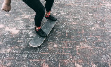 Genç bir adamın ayakları, tenis ve siyah pantolon ve kaykay konsepti.