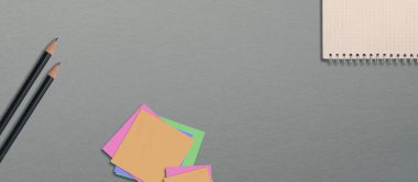 Masanın üzerinde siyah kalemler ve bir defter var. Okul malzemeleri. Gri arkaplan