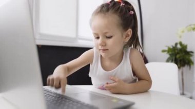 Küçük tatlı bir kız dizüstü bilgisayarına bir şeyler yazıyor.