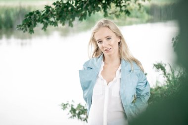 Nehrin kıyısındaki ağacın altında gülümseyen kadın. Yüksek kalite fotoğraf