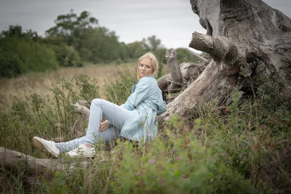 Uzun otların arasındaki bir ağaçta oturan genç kadın. Yüksek kalite fotoğraf