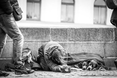 İnsanlar evsiz bir adamın ve iki köpeğinin yanından geçer, onları görmezden gelir, Prag