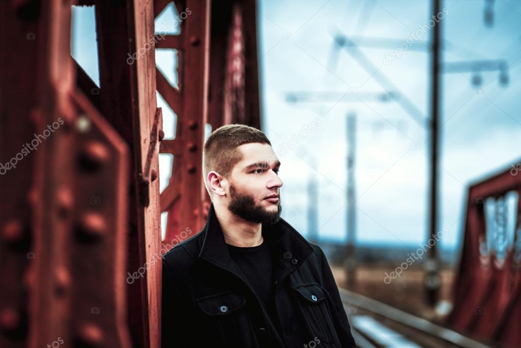 Man with beard walking on the railway