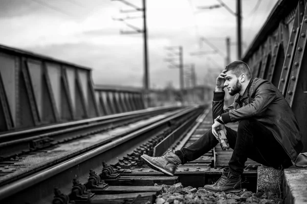 Man met baard, zittend op de spoorlijn — Stockfoto