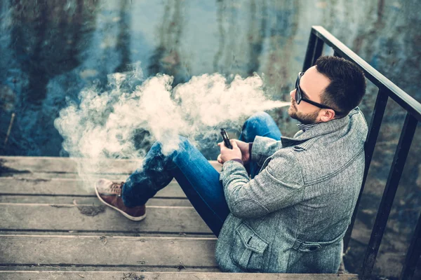 Man with beard vaping outdoor — Stock Photo, Image