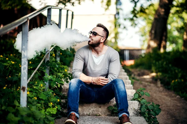 Muž v sluneční brýle vaping venkovní — Stock fotografie