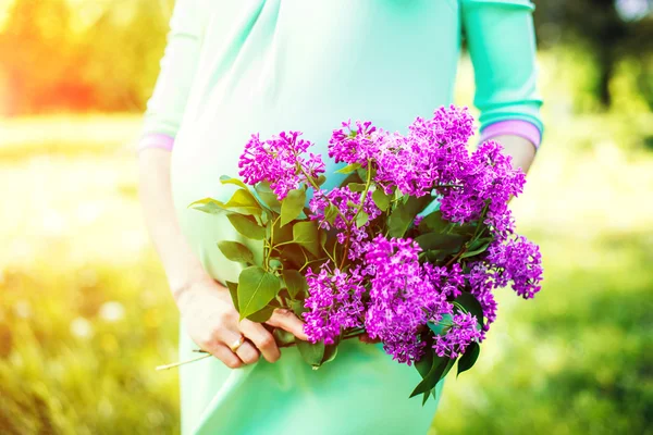 Preagnant woman holding purple flowers — Stock Photo, Image