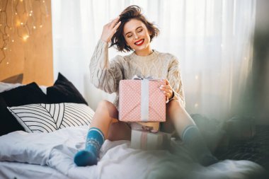 Yatağında hediye kutularıyla mutlu ve güzel bir esmer. Yeni yıl, Noel, doğum günü, Sevgililer Günü konsepti