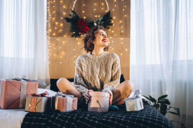 Yatağında hediye kutularıyla mutlu ve güzel bir esmer. Yeni yıl, Noel, doğum günü, Sevgililer Günü konsepti