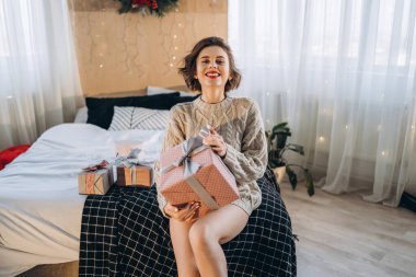 Yatağında hediye kutularıyla mutlu ve güzel bir esmer. Yeni yıl, Noel, doğum günü, Sevgililer Günü konsepti