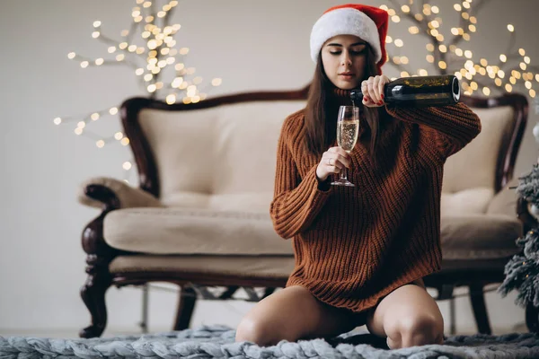 クリスマス かわいいです女の子でセーターとクリスマスの帽子とともにシャンパン屋内 — ストック写真