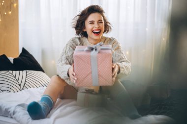 Yatağında hediye kutularıyla mutlu ve güzel bir esmer. Yeni yıl, Noel, doğum günü, Sevgililer Günü konsepti