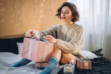 Yatağında hediye kutularıyla mutlu ve güzel bir esmer. Yeni yıl, Noel, doğum günü, Sevgililer Günü konsepti