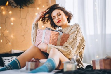 Yatağında hediye kutularıyla mutlu ve güzel bir esmer. Yeni yıl, Noel, doğum günü, Sevgililer Günü konsepti