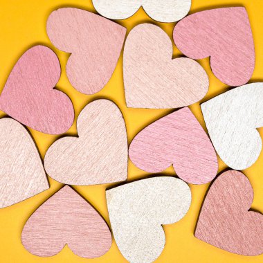 Parlak sarı arka planda kalp şeklindeki nesnelerin yaratıcı düzlüğü. Aşk konsepti